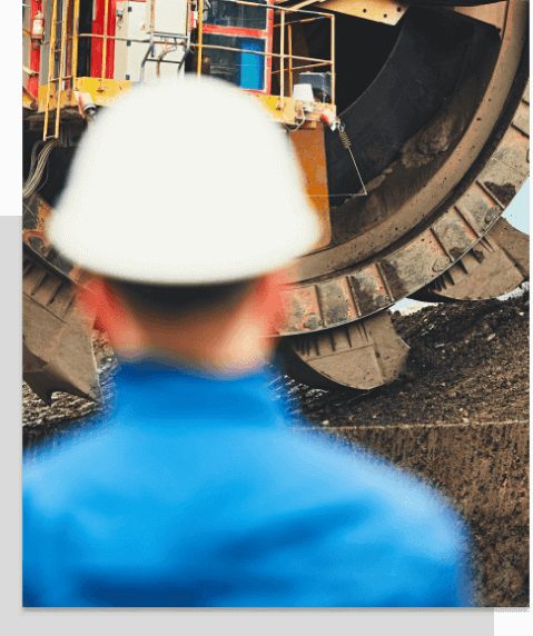 Skilled project management professional standing in front of Industrial Shredder Equipment at ADS Mining Services -Underground Coal Mining Operations